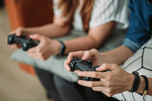 Asian chinese smiling sibling playing video games at home crop shot of two young adults hand holding game joystick game controller photos stock pictures, royalty-free photos & images