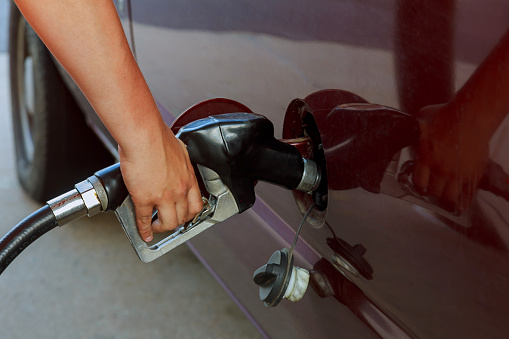 Man pumping gasoline car at gas station being filled with fuel on closeup