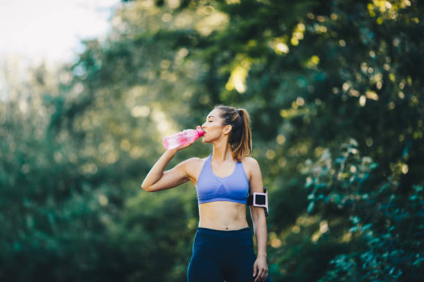 a jovem está bebendo água da garrafa, tendo uma pausa para correr. - flexibility business gymnastics exercising - fotografias e filmes do acervo