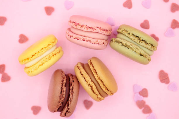 istock Close up macaroons with hearts on pink background 1296168305