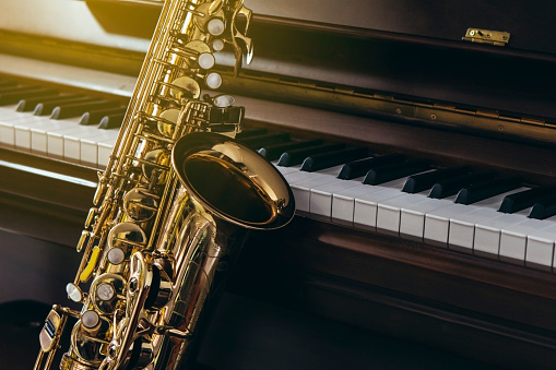 close up of alto saxophone  over piano keys  can be used for music background or  copy space