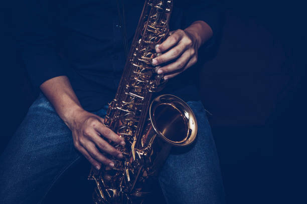 istock a young musician man hands hold and playing saxophone on black background 1296169769