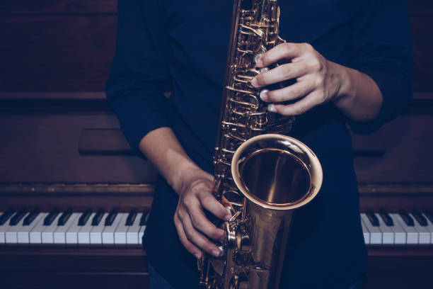 nahaufnahme von saxophon spieler hände spielen altsaxophon musikinstrument über dem klavier hintergrund - close up musical instrument saxophone jazz stock-fotos und bilder