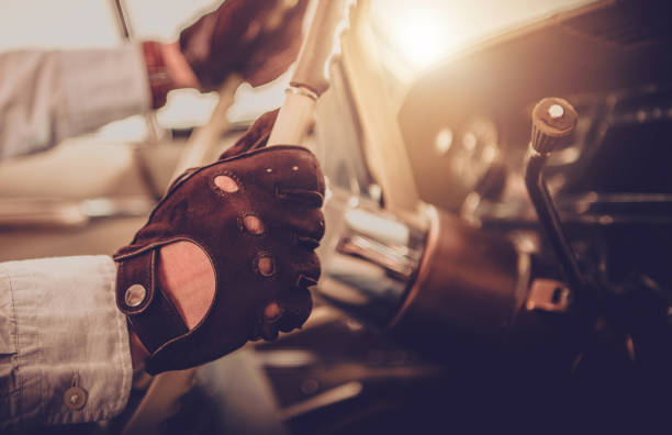 Vintage Vehicle and Caucasian Oldtimer Lover. Hands on Classic Car Steering Wheel Close Up. History of Automotive Concept.