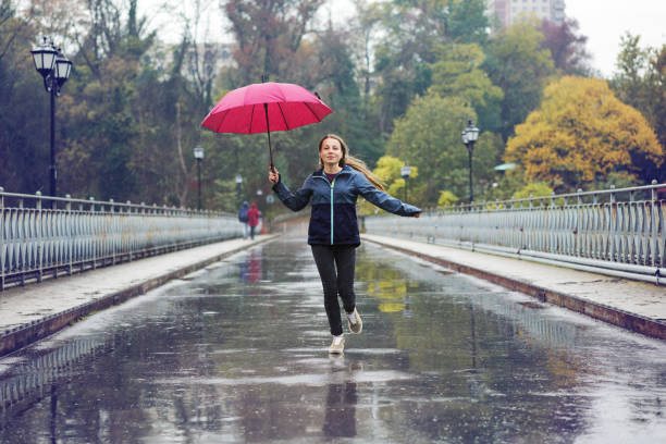 istock Woman with red umbrella having fun in rainy day 1296174079