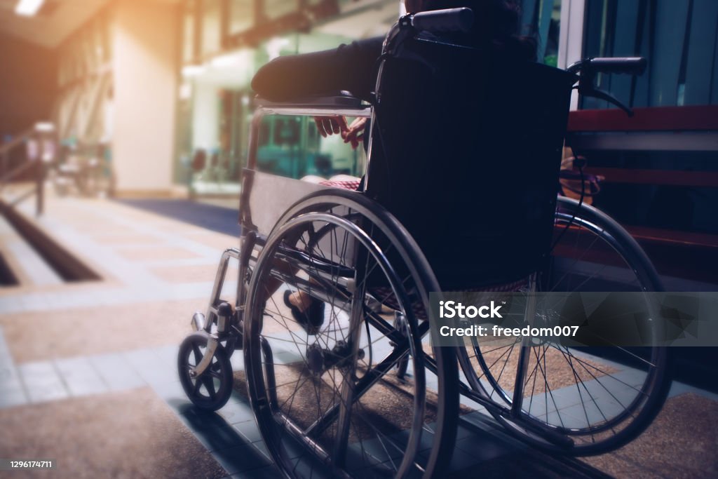 Woman sitting on wheel chair at hospital in the night Woman sitting on wheel chair at hospital in the night with copy space Wheelchair Stock Photo