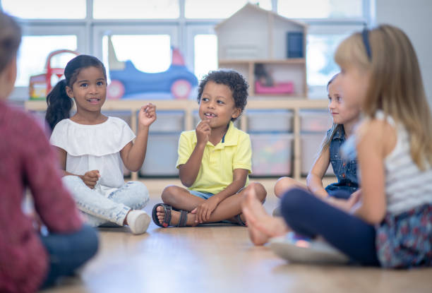 Circle time in preschool classroom A multi ethnic group of children are sitting on the floor in a circle for circle time in their classroom. They will be singing songs and reading stories with their teacher. literacy photos stock pictures, royalty-free photos & images
