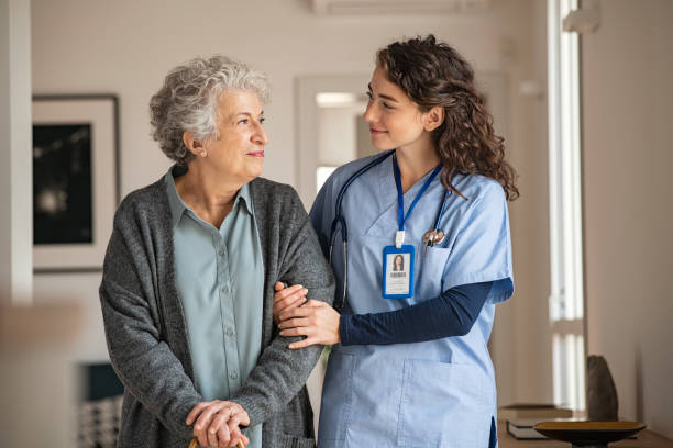 Caregiver assist senior woman at home Young caregiver helping senior woman walking. Nurse assisting her old woman patient at nursing home. Senior woman with walking stick being helped by nurse at home. pension photos stock pictures, royalty-free photos & images
