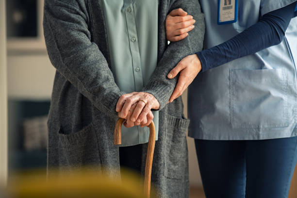 Nurse assisting senior with walking cane Close up hands of caregiver doctor helping old woman at private clinic. Close up of hands of nurse holding a senior patient with walking stick. Elder woman using walking cane at nursing home with nurse holding hand for support. old stock pictures, royalty-free photos & images