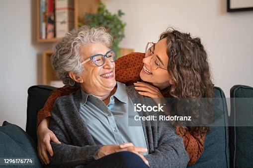 istock Grandmother and granddaughter laughing and embracing at home 1296176774