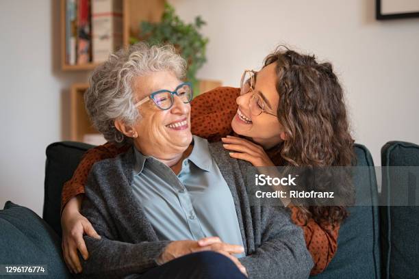 Grandmother And Granddaughter Laughing And Embracing At Home Stock Photo - Download Image Now