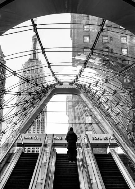 Entrance and exit escalator at Penn railroad station Manhattan, New York, USA - January 10, 2021: Entrance and exit for Penn Station on 33rd Street and 7th Avenue. New York commuters use Penn Station for comutes to and from Long Island, the city wide subway system and Amtrak. train station black and white stock pictures, royalty-free photos & images