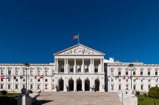 Lisbon, Portugal - January 10, 2021: View of the facade of the Assembleia da Republica (Portuguese Parliament), with the european union countries flags raised in order to sign the Portuguese presidency of the EU.