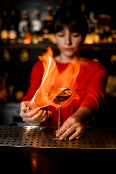istock female barkeeper holds glass on bar counter and sets it on fire 1296190106