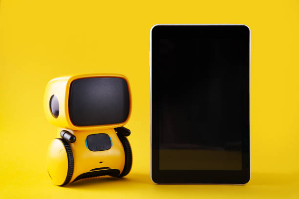istock Robot toy and Smart phone on yellow background. Chatbot concept. Copy space 1296190678