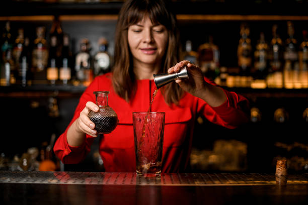 istock glass stands on bar and woman bartender pours drink from jigger into it 1296191689