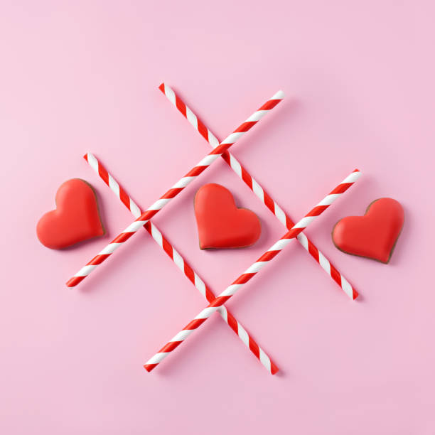 istock Tic-tac-toe with straws and red hearts on pink background 1296191705