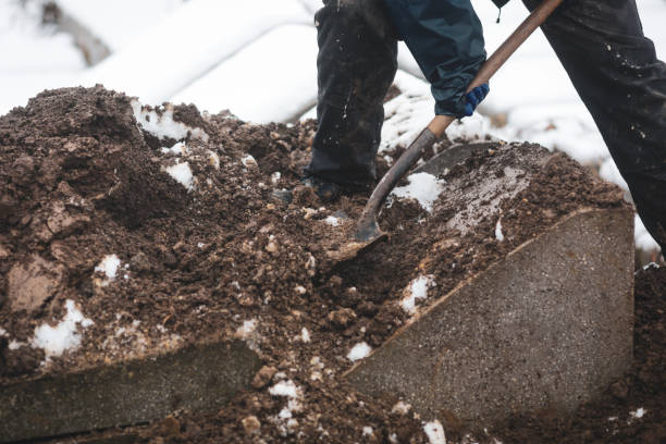 Details of a gravedigger covering a tomb with dirt with a shovel during a burial ceremony on a cold and snowy winter day. Details of a gravedigger covering a tomb with dirt with a shovel during a burial ceremony on a cold and snowy winter day. grave digger stock pictures, royalty-free photos & images