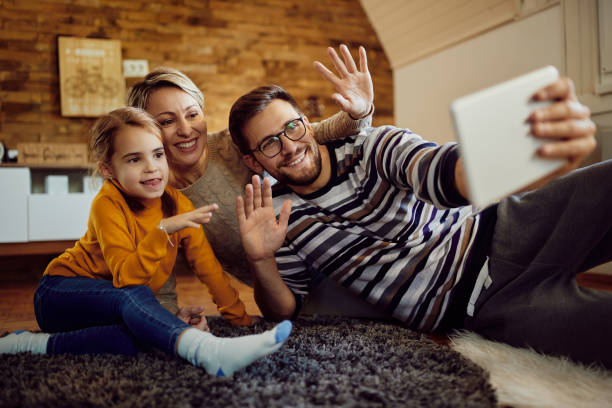 istock Cheerful family waving while having video call over touchpad at home. 1296191919