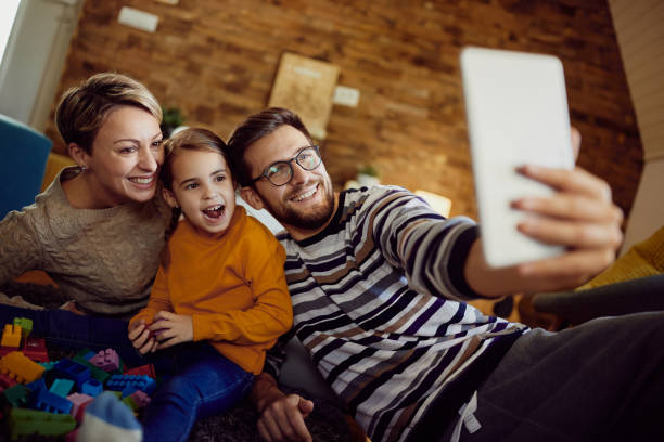 istock Cheerful family having fun while taking selfie with touchpad at home. 1296192363