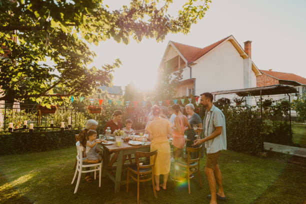 An outdoors family party Photo of multi generation family, having party in the backyard. It's a post covid gathering, out in the open to protect an elderly members of the family. garden parties stock pictures, royalty-free photos & images