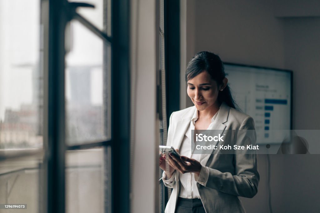 Beautiful Indian businesswoman using her mobile phone in the office Banking Stock Photo