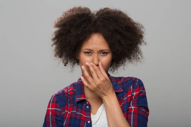 Portrait of young woman Portrait of young woman holding nose while standing against grey background. holding nose stock pictures, royalty-free photos & images