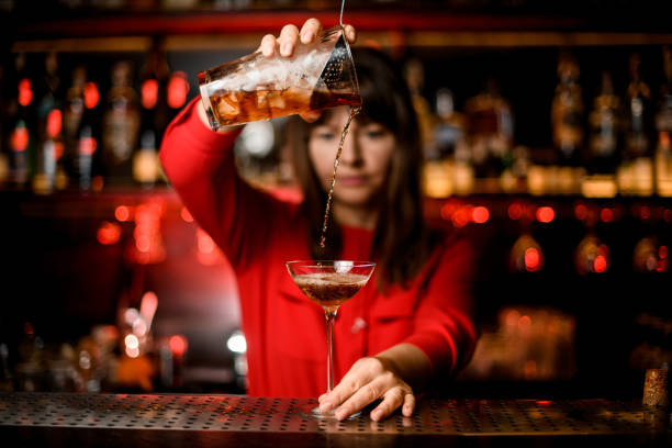 istock view on wineglass standing on bar and bartender holding mixing cup and accurate pours drink into it 1296194131