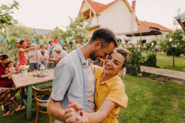 Anniversary dance Portrait of a couple who celebrates their anniversary, is dancing outdoors in their backyard while their family is having dinner in the background middle aged couple dancing stock pictures, royalty-free photos & images