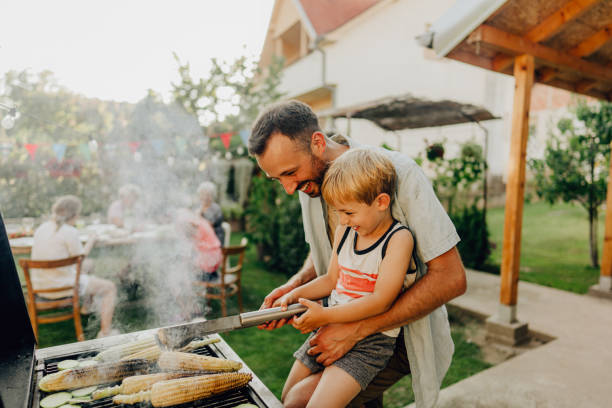 Barbecue party in our backyard Photo of father showing his boy how to grill summer fun stock pictures, royalty-free photos & images