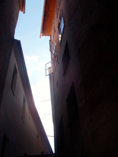 istock atrium, narrow dark lane with light from above 1296195202