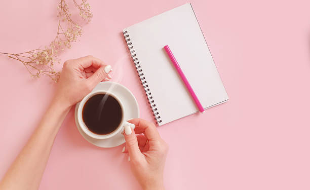 istock female hands holding a cup of coffee, notebook on a colored background 1296195795