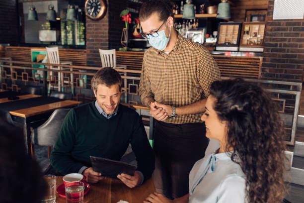 istock Waiter with a protective mask taking an order from a business group 1296196534