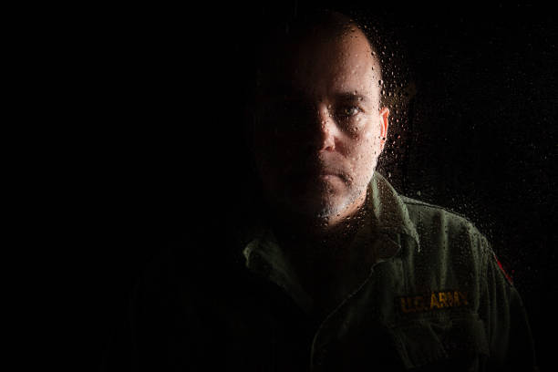 Dramatic Veteran Portrait With Raindrops Dramatic portrait of a veteran behind a window with raindrops to further enforce the sullen look of depression and sadness. post traumatic stress disorder photos stock pictures, royalty-free photos & images