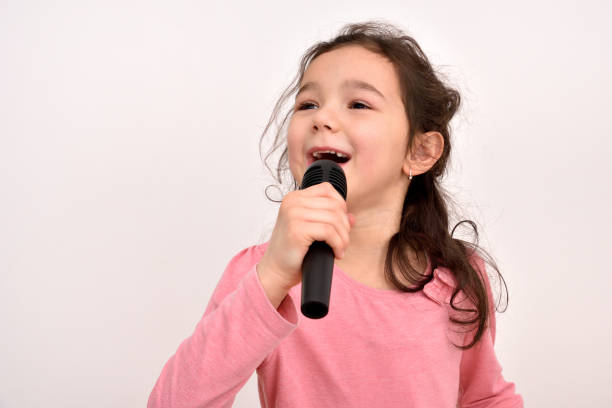 istock Young girl with a microphone singing 1296198424