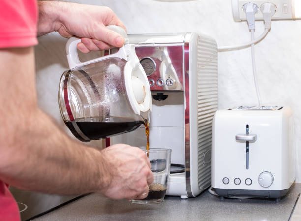 istock A middle-aged Caucasian man, made coffee in a coffee maker and pours it into a glass mug. 1296200879