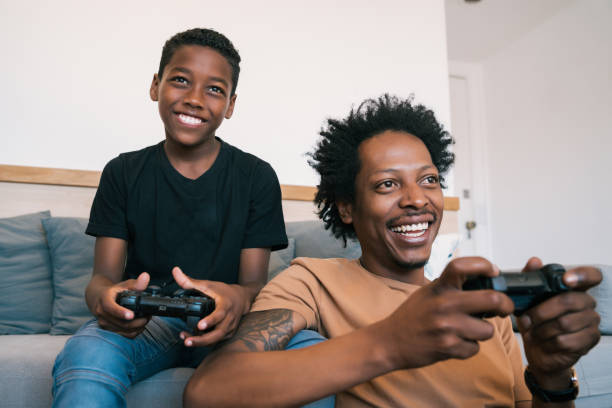 istock Father and son playing video games together at home. 1296202243
