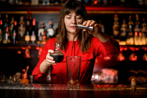 istock glass stands on bar and woman bartender accurate pours drink from jigger into it 1296202623