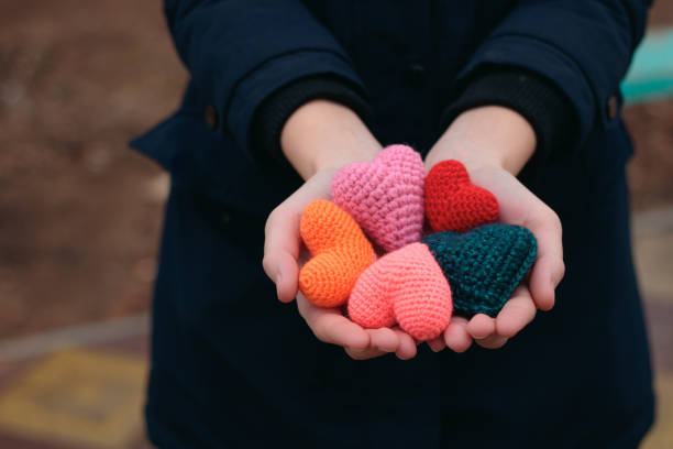 Knitted heart in hand. Many hearts in a woman's palm. Take my love. stock photo