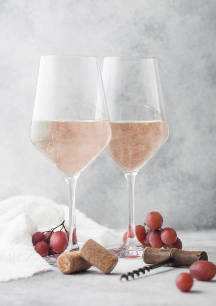istock Glasses of rose pink summer wine with corks, grapes and corkscrew on light background. 1296204873