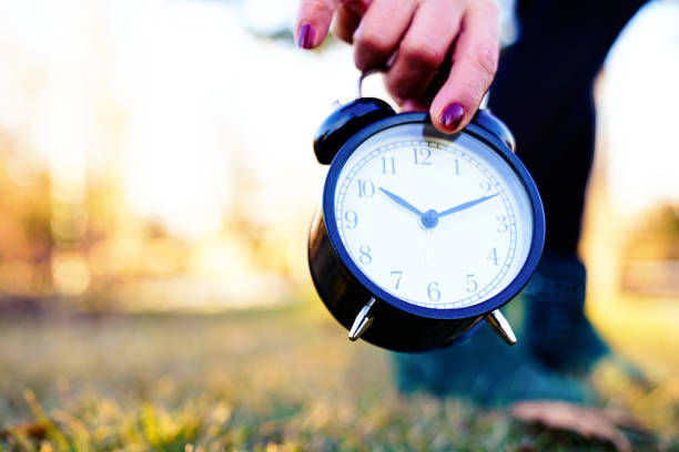 hand holding black alarm clock, outdoor