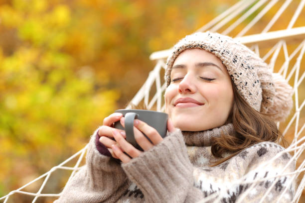 istock Relaxed woman smelling coffee on hammock in autumn 1296210277