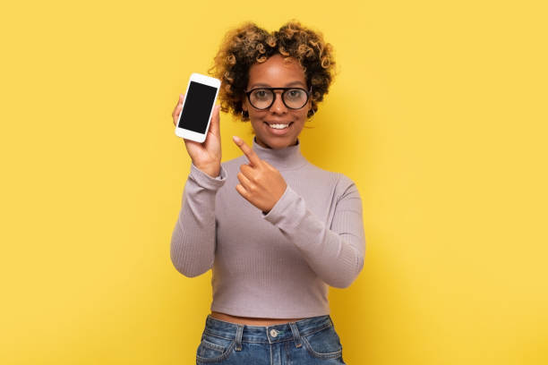 istock Excited african american woman pointing at smartphone with empty screen. 1296210319