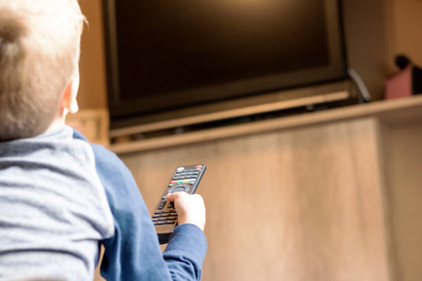istock Small boy changing channels on TV at home. 1296211913