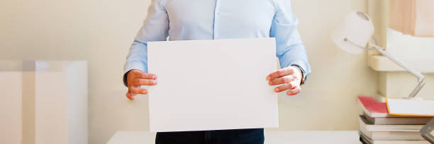 istock man holding a poster, copy space, concert message in the office 1296213675