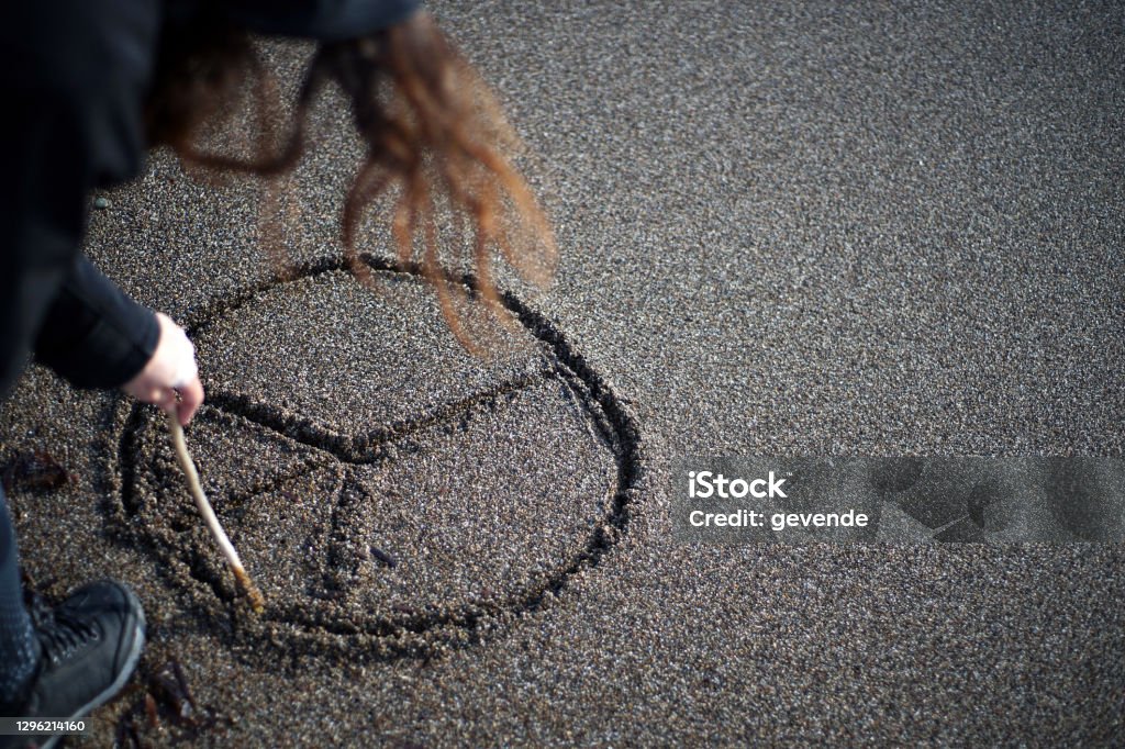 drawing on sand Young woman at the baech draws symbols on sand Music Festival Stock Photo