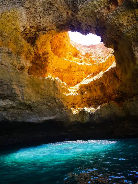 Sun goes through a hole of the Benagil Cave, Portugal, giving a spectacular blue color to the sea water.