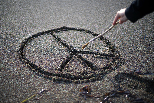 Young woman at the baech draws symbols on sand