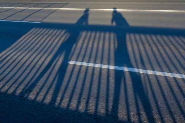 istock Shadows of men walking outdoors on road. 1296215725