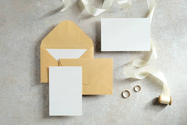 istock Empty wedding invitations cards mockups, envelopes, ribbon and rings on concrete table. Flat lay, top view. 1296216577